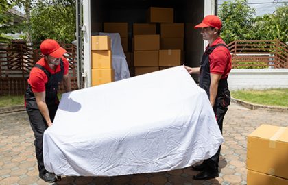 Portrait of two movers unloading boxes and furniture from a pickup truck.