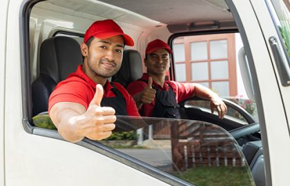 Portrait of two movers unloading boxes and furniture from a pickup truck.